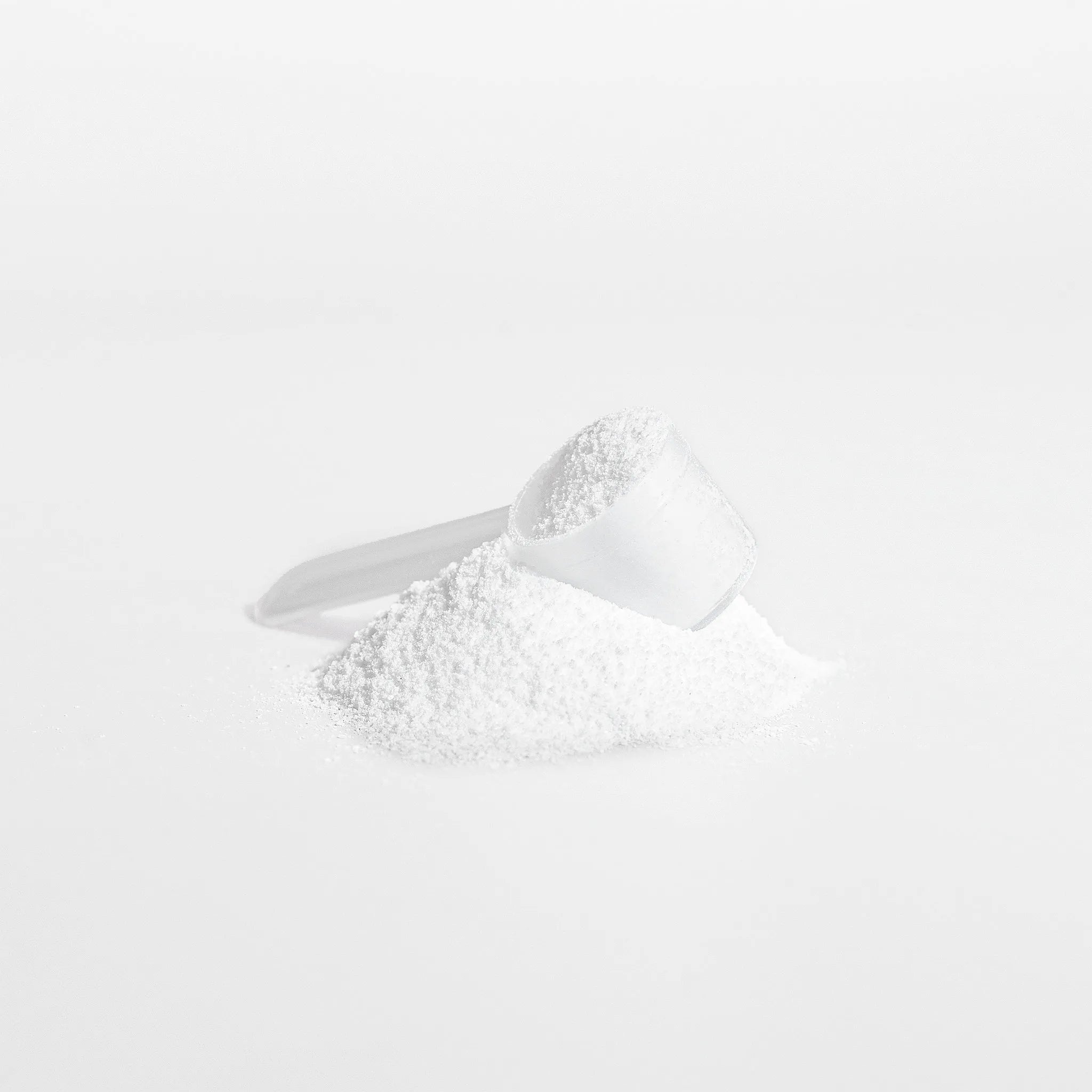 White powder in a measuring spoon on a white background
