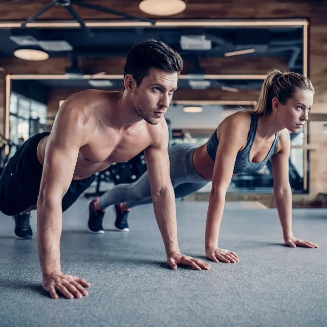 Man and woman doing push-ups in a gym setting